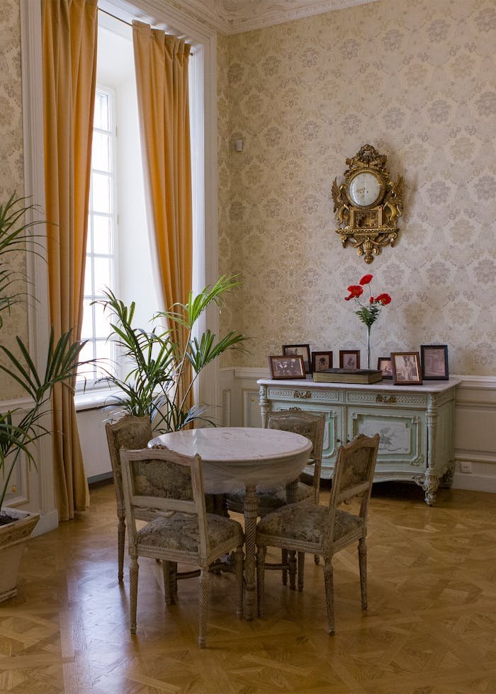 Charming vintage room with antique furniture, adorned with a gilded clock and large window.
